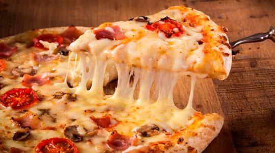 Uma deliciosa pizza de queijo, tomate e azeitona preta sobre uma bela tabua de madeira.